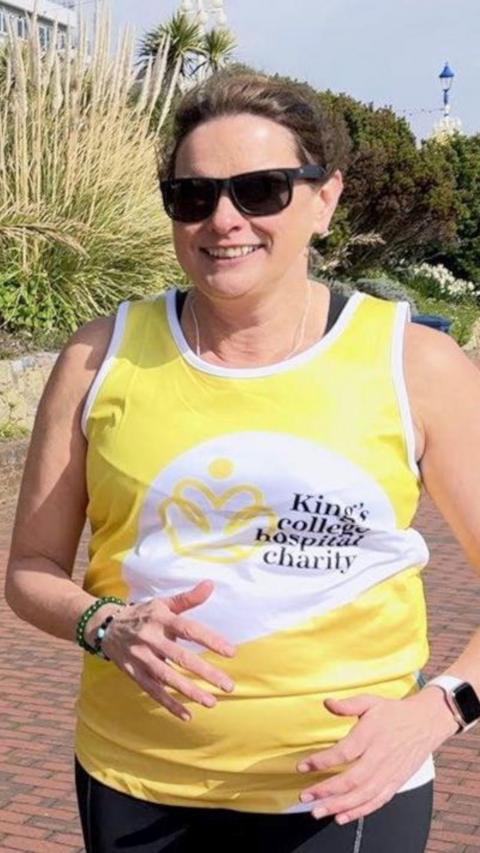 A woman in a yellow vest running on a promenade