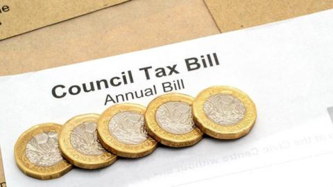 A stock image of the top of a generic council tax bill, with five £1 coins sitting on it.