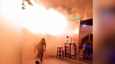 Someone runs from flames erupting from a bar doorway