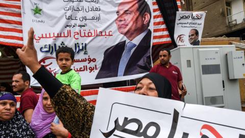 A supporter of Abdul Fattah al-Sisi makes a victory gesture outside a polling station in Giza, Cairo (28 March 2018)