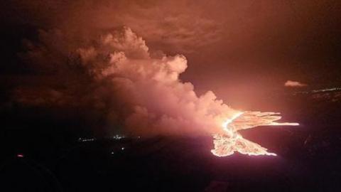 Magma and smoke pour from a fissure in the earth in Iceland
