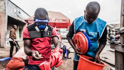 Health workers wear protective gear to mix water and chlorine in Goma