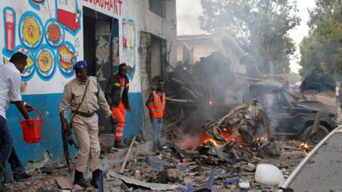 Somali security officers secure the scene of a suicide car bomb explosion