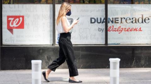 Woman walks in front of a Walgreens