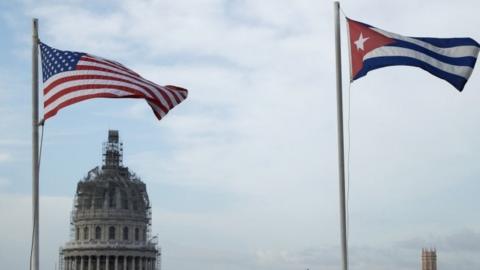 US and Cuban flags fly side-by-side on the roof of the Iberostar Hotel Parque Central near El Capitolio (background) in the historic Old Havana neighborhood (20 March 2016)