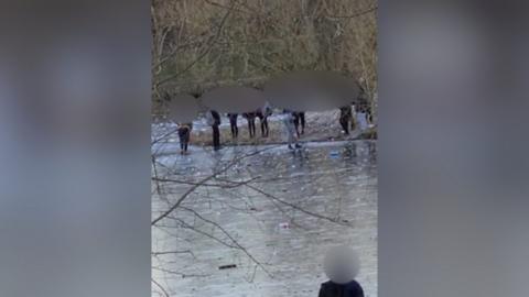 A still from a video which shows children playing on a frozen lake