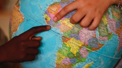 Globe with hands pointing to countries