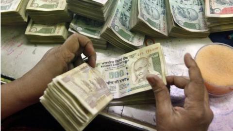 An employee counts Indian currency notes at a cash counter inside a bank in Kolkata June 18, 2012.