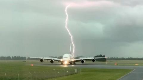 Lightning bolt behind the Emirates A380 plane at Christchurch Airport