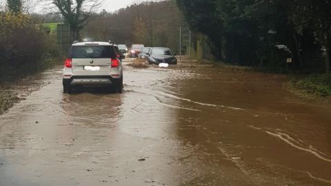 Cars driving through floodwater on the A35 at Winterborne Abbas