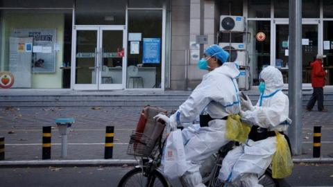 Pandemic prevention workers on a bike in Beijing