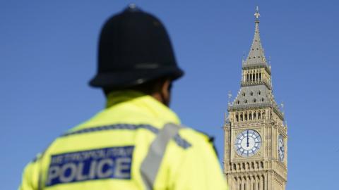 A police officer standing in from of Big Ben in Parliament Square.