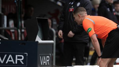 Referee David Dickinson checks the monitor and awards Celtic a penalty during a cinch Premiership match between St Mirren and Celtic at the SMiSA Stadium