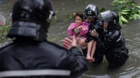 Police officers rescue a child from a flooded street in Hong Kong