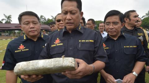 Budi Waseso (C), Indonesian chief of criminal investigation division, holds a seized marijuana block at the national police headquarters in Jakarta on May 11, 2015.
