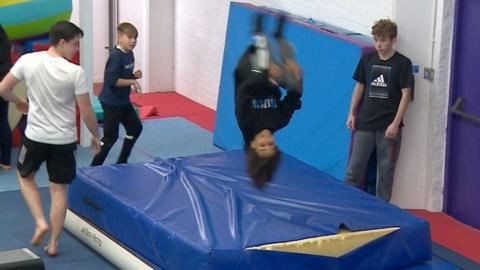 Child performing flip onto mats