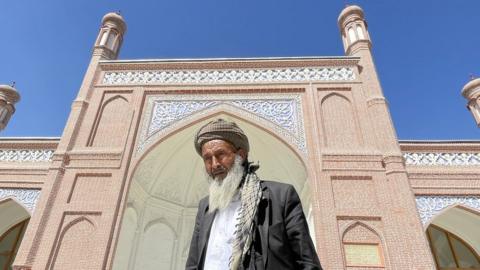 A man standing outside Eid Gah mosque