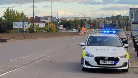 A police car and scene behind