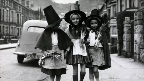 Tair Gymraes ddireidus yn dathlu Dydd Gŵyl Dewi yn Llandudno a chenhinen i bob un