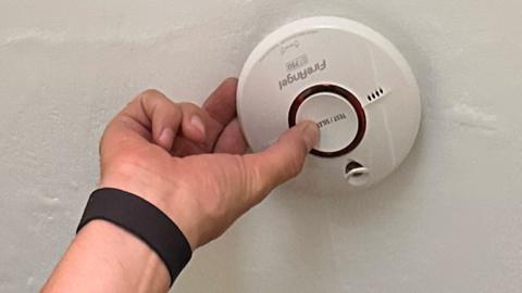 Firefighter testing smoke alarm