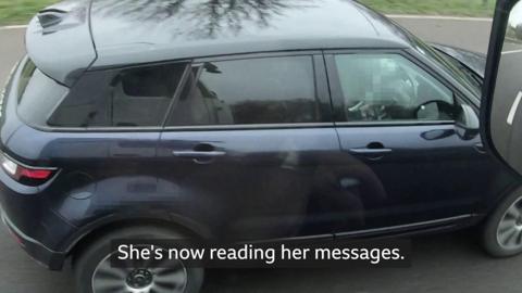 A woman reading phone messages while driving