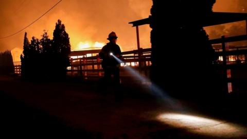 A firefighter runs along a dirt road during the wind-driven Kincade Fire in Windsor, California, October 27, 2019