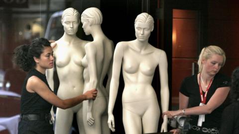 Women moving shop mannequins