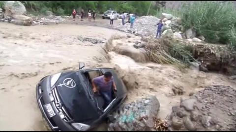 A survivor emerges from a car washed away by flooding in Peru