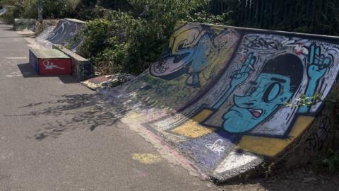 Skateboarding ramps with graffiti painted on in the sun