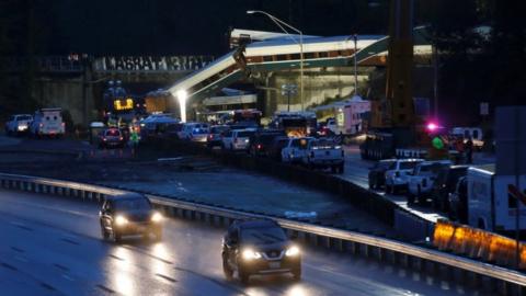 Night-time shot of the crash scene shows the carriages still over-hanging, surrounded by emergency services.