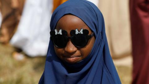 A girl wearing a headscarf and sunglasses celebrating Eid
