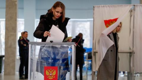 A Russian woman casts her ballot during the presidential elections at a polling station in Moscow, Russia