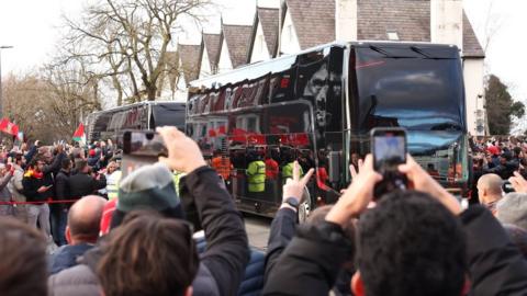 Fans take pictures as the Manchester United team bus arrives at Anfield