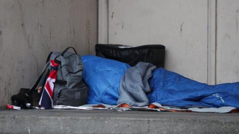 Homeless person's sleeping bag and belongings in doorway