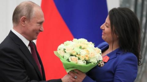 Russian President Vladimir Putin presents flowers to editor-in-chief of Russian broadcaster RT Margarita Simonyan in May