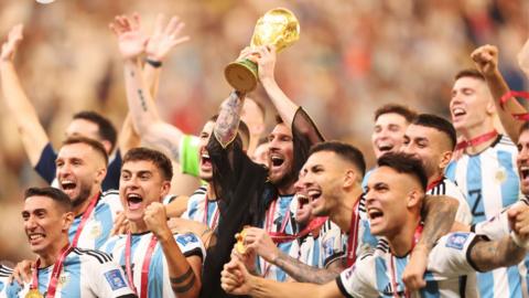Lionel Messi, surrounded by Argentina team-mates, lifts the World Cup trophy