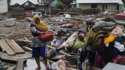 A woman walks among debris in a devastated area after a tsunami hit Sunda Strait in Sumur, Banten