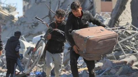 Palestinians walk through rubble in Khan Younis (13/03/24)