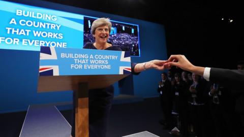 Theresa May being handed a cough sweet at the 2017 Conservative Party Conference