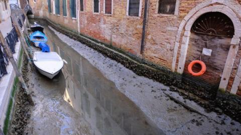 Boats are seen in a canal during an exceptionally low tide