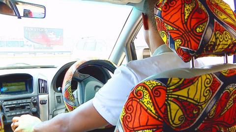 Ugandan man driving car with decorated interior
