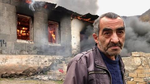 Man standing in front of burning house