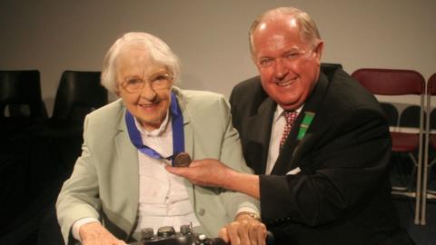 Eirwen Gwynn yn derbyn ei medal gan Hugh Thomas yn 2006