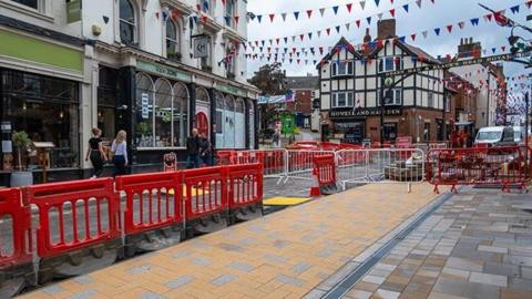 Roadworks in Ashbourne, with red fencing and barriers in the town, in front of the Howell and Marsden
