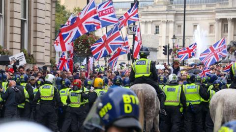 Protesters taking part in a 'Unite the Kingdom' rally are held back by police officers, some on horses, in central London.