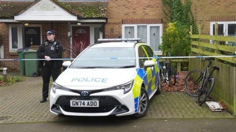 A police car and tape across a house in Folkestone. A police officer stands behind the tape next to the car