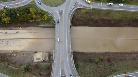 A flooded A421 showing water on the road and a bridge over road