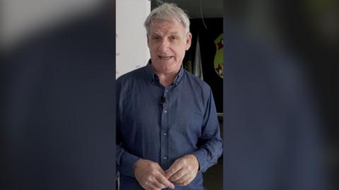 Jonathan Head looks at the camera. He wears a blue long-sleeve shirt.