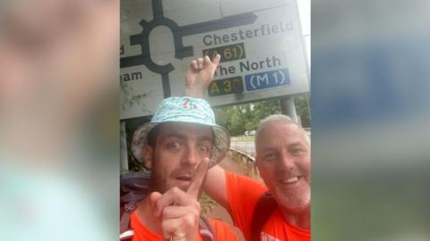 Jordan Brooks and Innes Miles pointing to a sign for Chesterfield