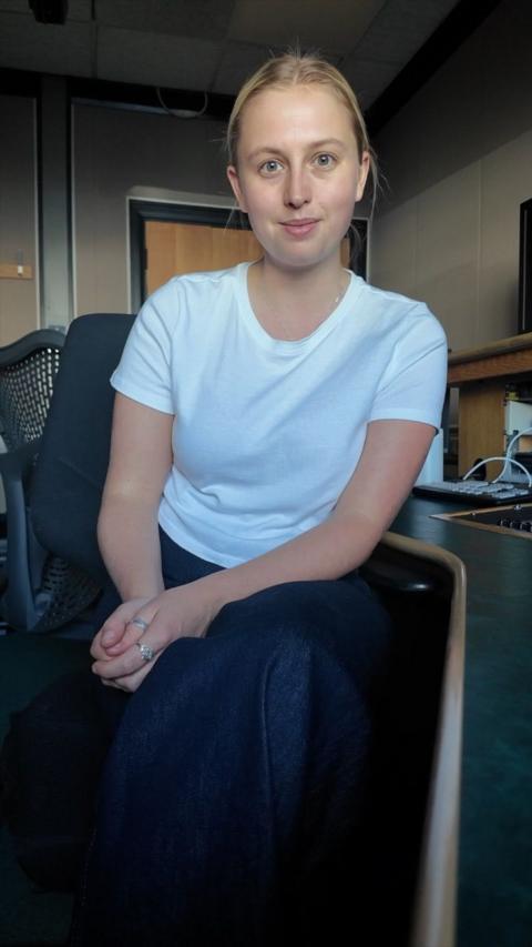 a white girl with blonde hair smiling at the camera in a white t-shirt and jeans